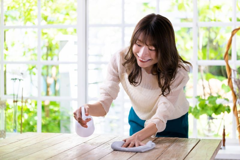 テーブルを除菌スプレーで拭く女性