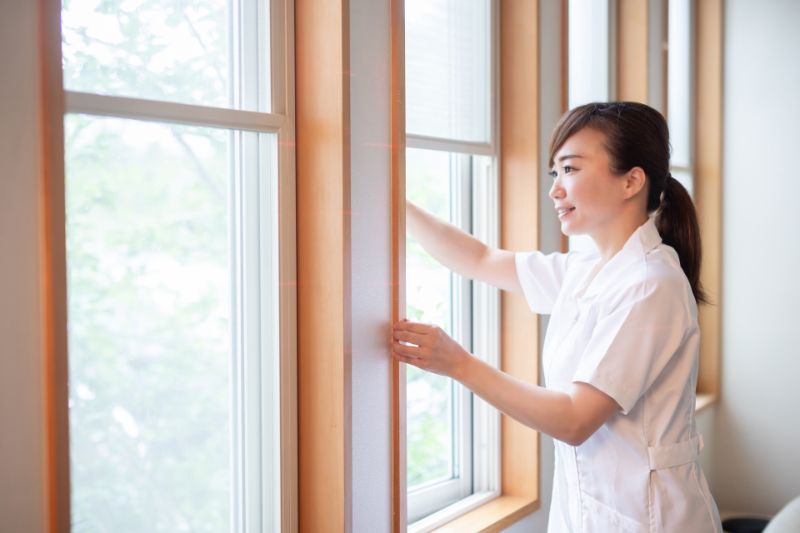 窓を開けて換気する女性